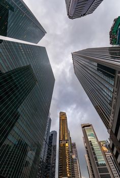 Glass Facades of skyscrapers of the financial district of Singapore on a cloudy evening, bottom view, wide lens, city center, building of large companies without logos. High quality photo