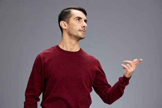 man in a red sweater gesturing with hands posing Gray background. High quality photo