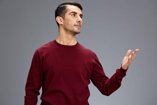 manager in a red sweater gesturing with hands posing Gray background. High quality photo