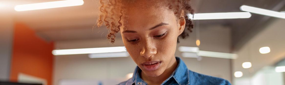 Close up of young businesswoman holding smartphone and looking on screen in the office