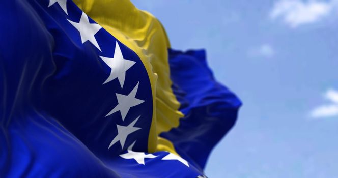 Detail of the national flag of Bosnia and Herzegovina waving in the wind on a clear day. Democracy and politics. Selective focus. Bosnia, is a country at the crossroads of south and southeast Europe