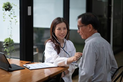 Stethoscope exam. Attractive cheerful asian female doctor listening to the elderly while using stethoscope.