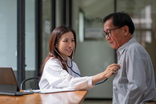 Stethoscope exam. Attractive cheerful asian female doctor listening to the elderly while using stethoscope.