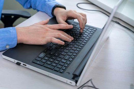 Close up of mans hand typing on laptop keyboard, author writing on pc computer, businessman programmer working concept