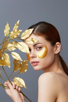 woman golden leaves luxury skin care face patches bare shoulders close-up Lifestyle. High quality photo