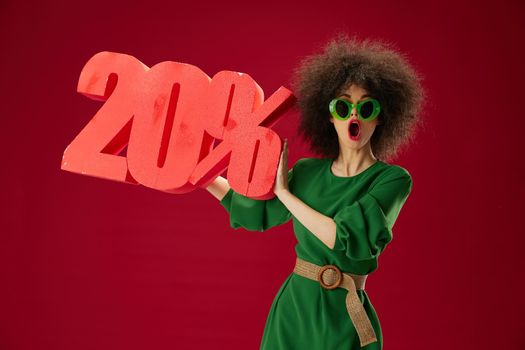 Pretty young female holding red twenty percent discount advertising color background unaltered. High quality photo