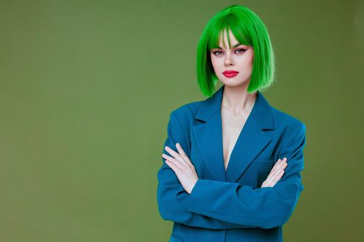 Positive young woman wearing a green wig blue jacket posing green background unaltered. High quality photo