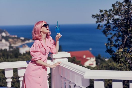 attractive woman in a pink dress in sunglasses with a cocktail Happy female relaxing. High quality photo