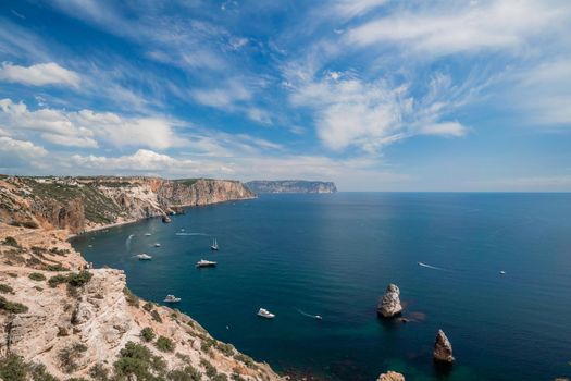 Two rocks stick out of the water in the middle of the turquoise sea. Scenic ocean view. Speed boat sails on the sea. High quality photo.