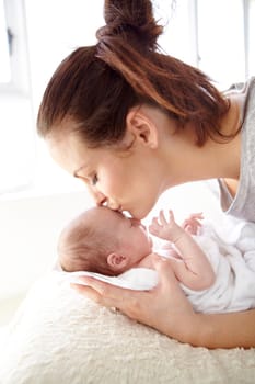 Closeup shot of a mother tenderly kissing her newborn baby.