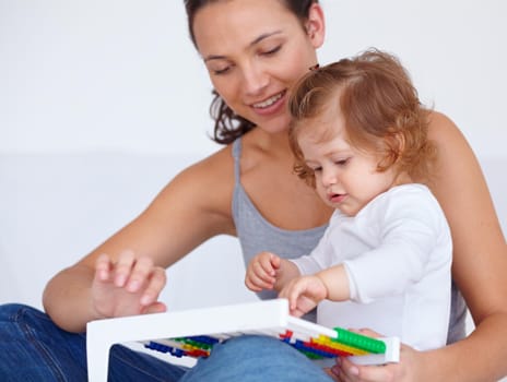 A cute baby girl being taught by her mother how to use an abacus.