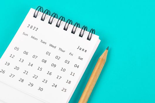 The June 2022 desk calendar with wooden pencil on light blue background.