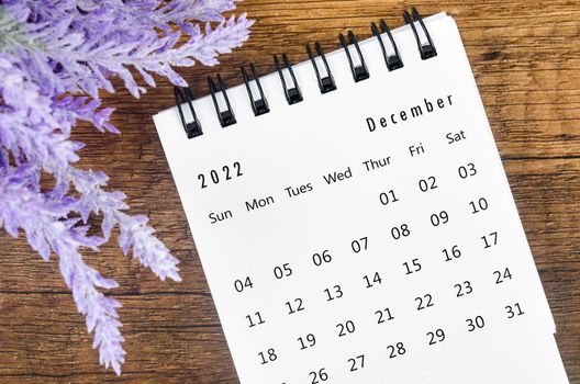 The December 2022 desk calendar with flower on wooden background.