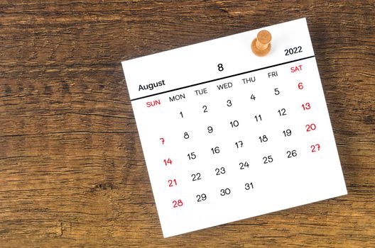 The August 2022 calencar and wooden push pin on wooden background.