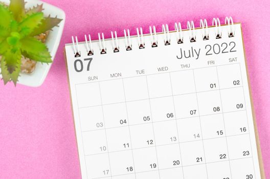 The July 2022 desk calendar with plant pot on pink background.