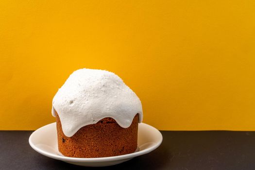 Kulich at home. Getting ready for Easter at home. Easter cake, decorated with icing, are on a yellow background