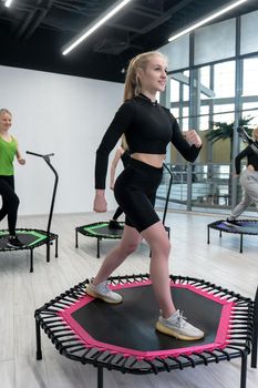 Trampoline for fitness girls are engaged in professional sports, the concept of a healthy lifestyle jumping trampoline woman fitness jump healthy, in the afternoon workout health in lifestyle and body movement, club muscular. Mini cute motion, center