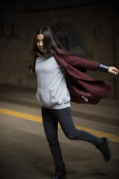 Photo of young woman in night subway walking forward. Full body