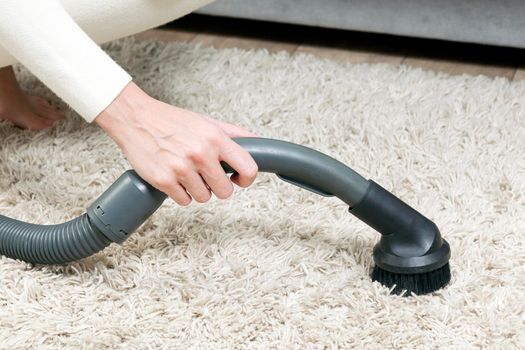 Woman is vacuuming bedroom carpet.