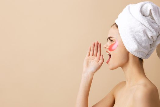 pretty woman pink patches on the face with a towel on the head beige background. High quality photo