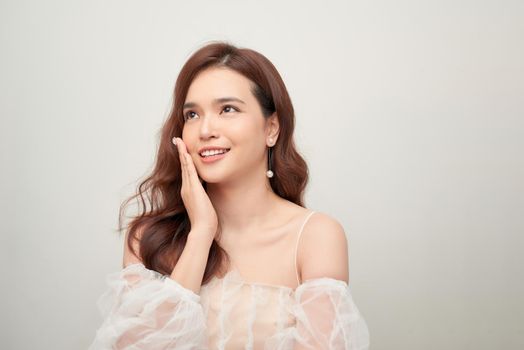 Beautiful portrait of asian young woman in white blouse on grey background.