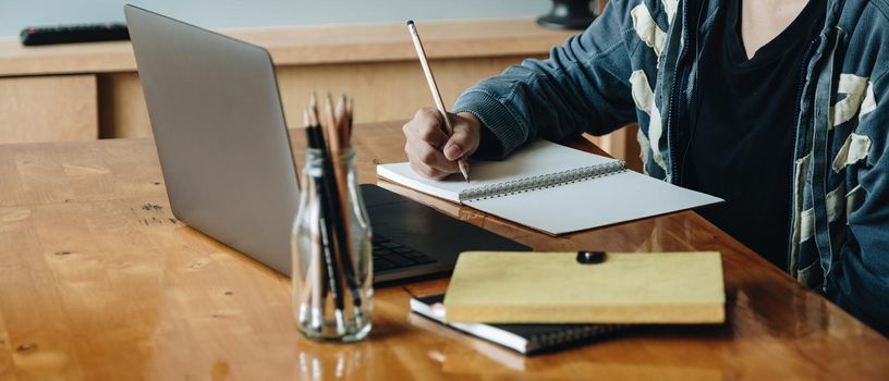 Cropped photo of woman writing making list taking notes in notepad working or learning on laptop indoors- educational course or training, seminar, education online concept.