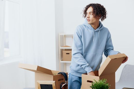 handsome guy in headphones unpacking with box in hand sorting things out. High quality photo