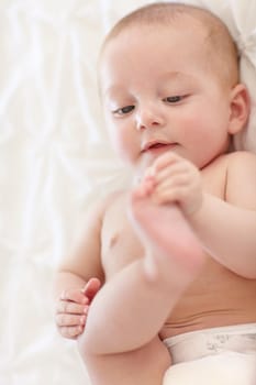 Sweet little baby lying down and touching its feet.