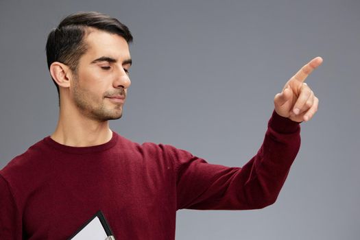 successful man with closed eyes points to the side with the finger in a red sweater folder for papers. High quality photo