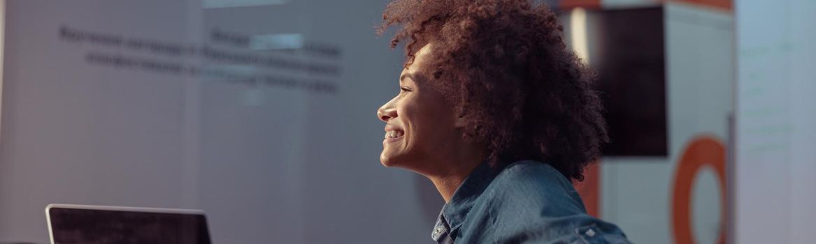 Side view of happy Afro American lady working at her workplace with laptop. Business, employment concept