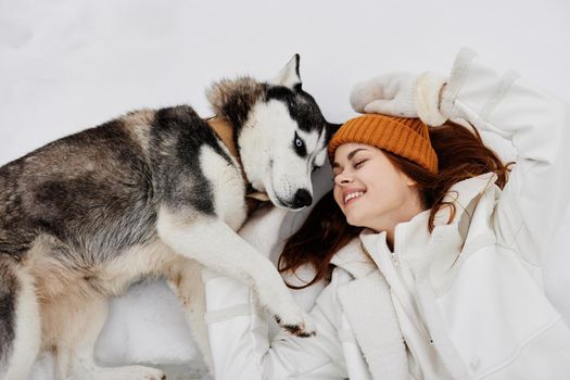 young woman in the snow playing with a dog fun friendship Lifestyle. High quality photo