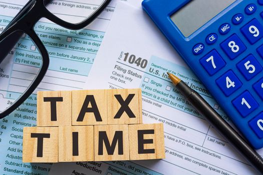 Text on Alphabet wooden block cube with Tax forms 1040. U.S Individual Income Tax Return on a desk. Business and tax concept. Time to pay tax in year.