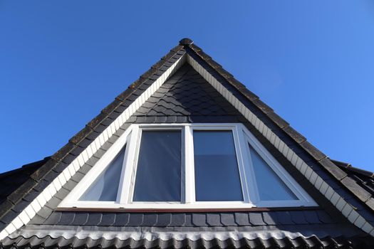 Open roof window in velux style with black roof tiles