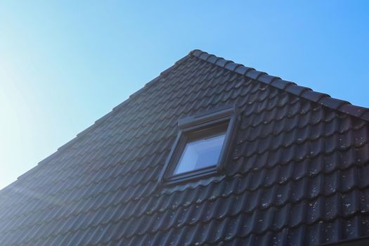 Open roof window in velux style with black roof tiles