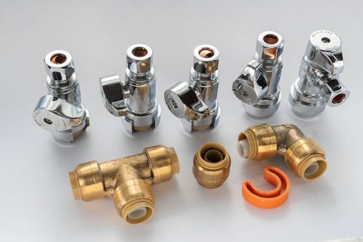 Brass plumbing fittings, pipes, elbows, and end caps, top and side connection faucets against a white background