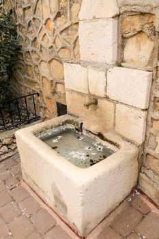 Stone fountain of fresh water with almond flower petals in Benifato village, Alicante, Spain