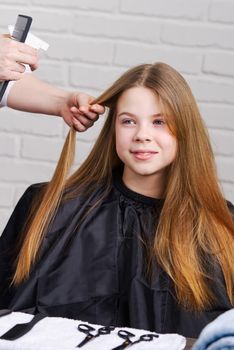Hairdresser making a hair to cute girl in hair salon. Young girl at hairdresser. beauty salon concept