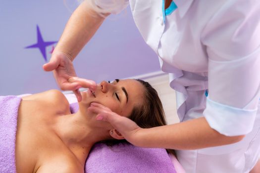 Relaxing massage. European woman getting facial massage in spa salon, side view.