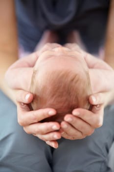 Closeup cropped shot of a mother cradling her baby on her lap.