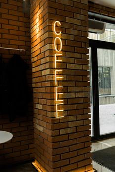 Coffee neon sign emblem in neon style on brick wall background.