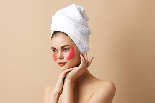 young woman pink patches on the face with a towel on the head beige background. High quality photo