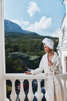 Attractive young woman in a white robe on the balcony bit on green nature Relaxation concept. High quality photo