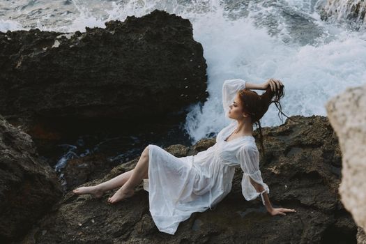 Barefoot woman in a white dress lying on a stone in a white dress nature landscape. High quality photo