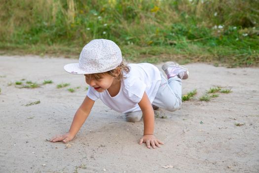 portrait of little toddler crawling in sand in counrtyside