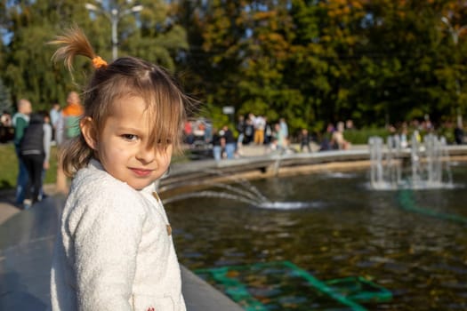 funny little girl playing in autumn public park in sunsine. family day