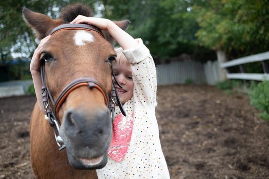 portrait of girl hugging pony horse muzzle at ranch. human and animal friendship