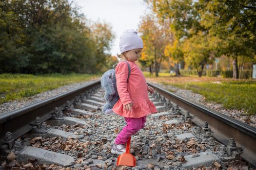 little girl walk on railroad trucks alone autumn day