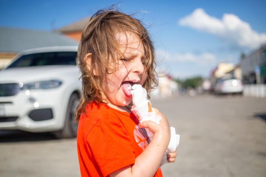 Cheerful child licking a vanilla ice cream on the beach. ice cream melts and flows