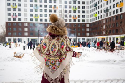 rear view woman in traditional russian scarf carry hot pancakes blini at winter festival maslenitsa outdoors