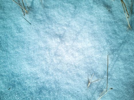 abstract natural texture of snow and dry grass. top view of snow covered field pattern